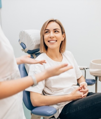 Young woman in dental chair smiling at her dentist