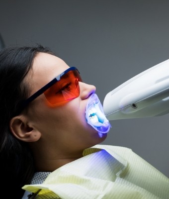 Woman getting her teeth professionally whitened by cosmetic dentist
