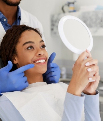 Young woman in dental chair seeing her smile in a mirror