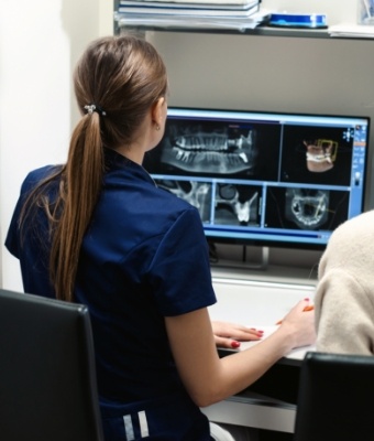 Dental team member looking at digital dental x rays on computer