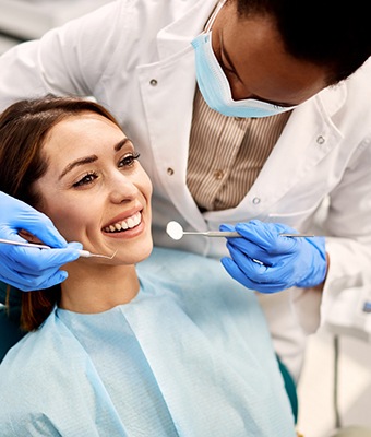Dentist examining smiling patient's teeth during consultation