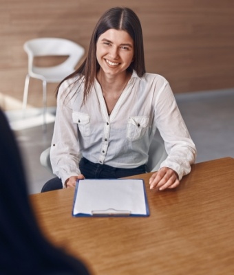 Smiling woman sitting at desk with clipboard