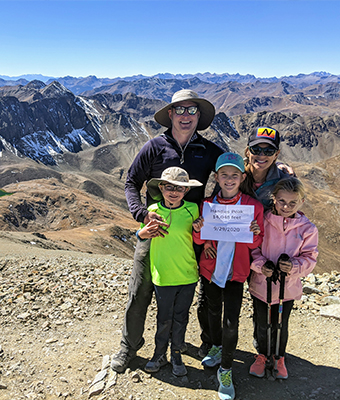 Doctor Battle and his family smiling on hike with mountains in background
