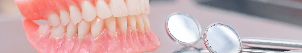 Denture next to two dental mirrors