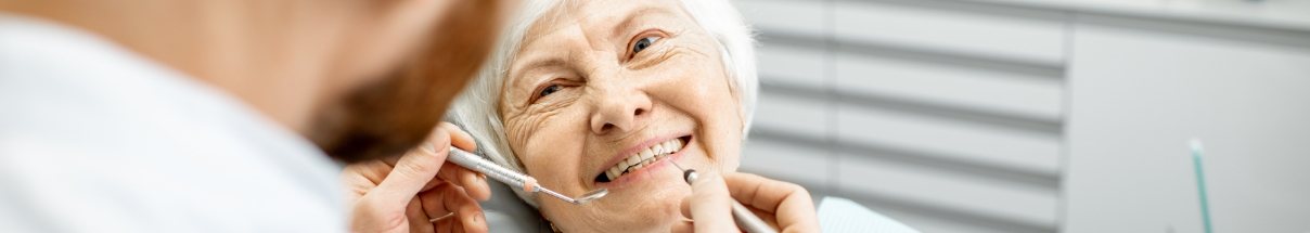 Senior woman smiling at her dentist after restorative dentistry in Claremore