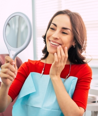 Young woman in dental chair seeing her smile in a mirror