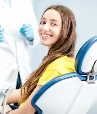 Young woman in yellow blouse smiling in dental chair