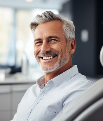 Senior man smiling while sitting in dental chair